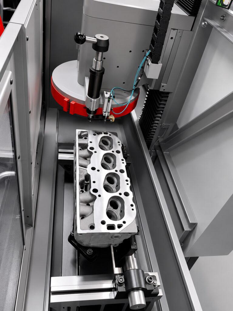 Overhead view inside the Winona Van Norman SM-E Surface Milling Machine showing a resurfaced engine block positioned on the work table after the machining process.