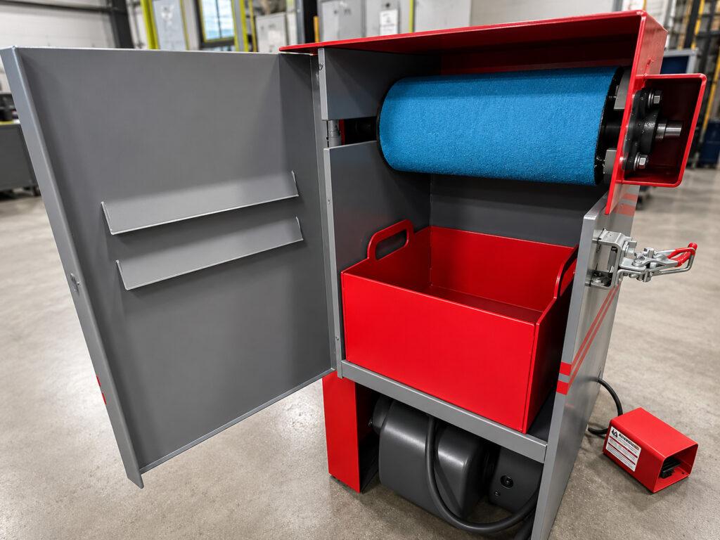 Close-up of the debris collection tray on a Winona Van Norman Platen Grinder designed to capture grinding dust and material during surface finishing operations.
