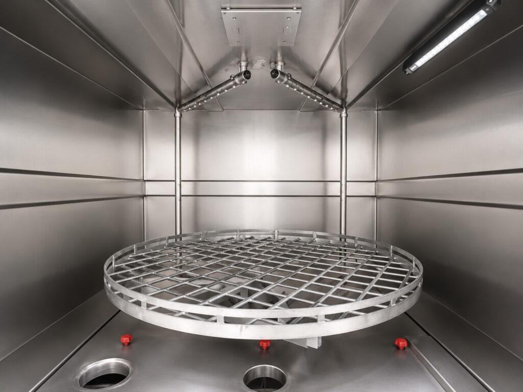 Interior view of a Winona Van Norman Stainless Steel Washer showing the wash chamber, rotating table, and high-pressure spray system designed for thorough parts cleaning.