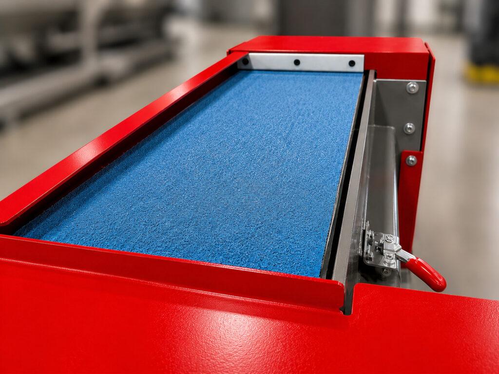 Close-up of the abrasive sanding belt on a Winona Van Norman Platen Grinder used for precision surface grinding and material removal.