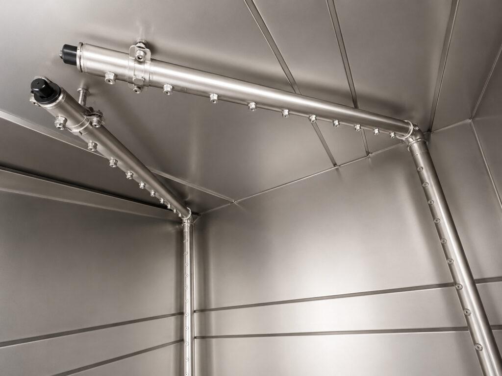 Close-up of the high-pressure sprayers on a Winona Van Norman Stainless Steel Washer delivering heated cleaning solution for complete parts cleaning.