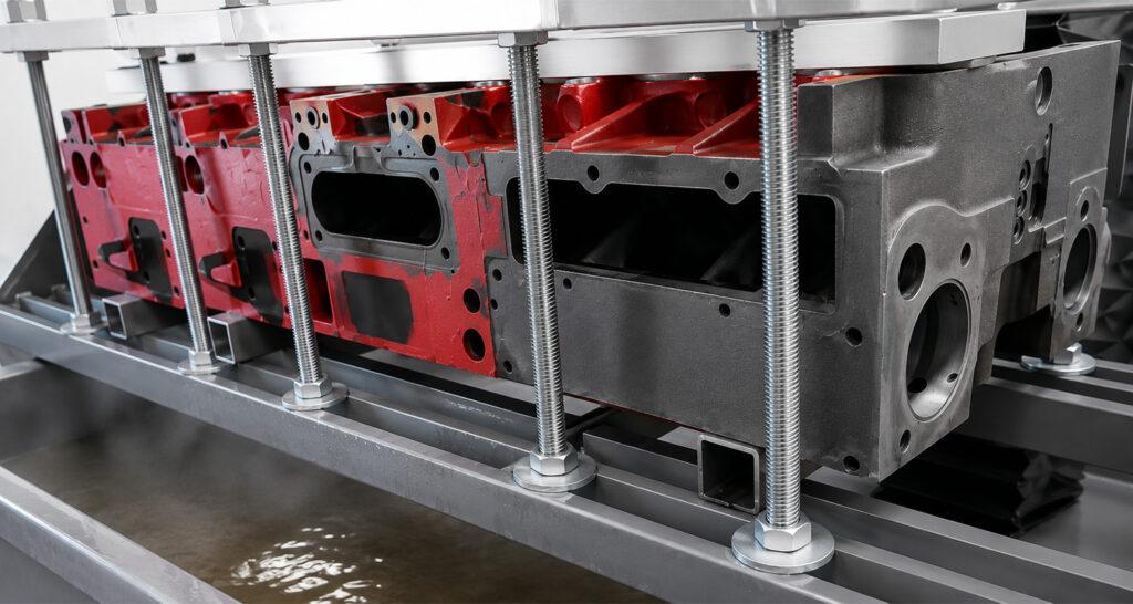 Engine block positioned on the work table of the Winona Van Norman CHT1240 Pressure Tester, ready for precision leak and crack testing.