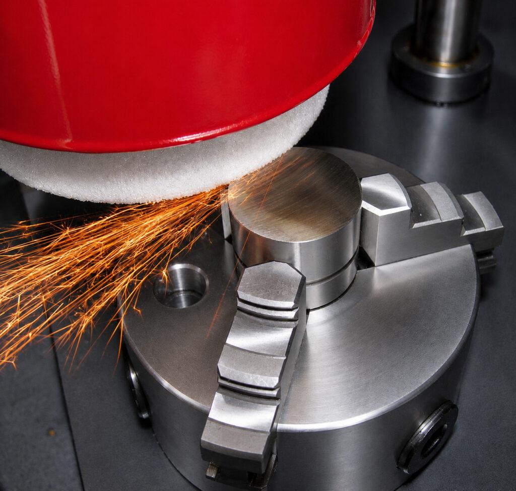 Action shot of the Winona Van Norman PCGX Pre-Cup Surfacer resurfacing a diesel cylinder head with visible sparks during the machining process.