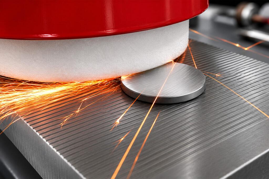 Action shot of the Winona Van Norman PCGX Pre-Cup Surfacer resurfacing a diesel cylinder head with visible sparks during the machining process.