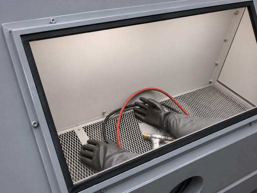 Close-up of the safety gloves and blasting gun on a Winona Van Norman GB601 Glass Bead Blaster used for safe, controlled glass bead blasting.